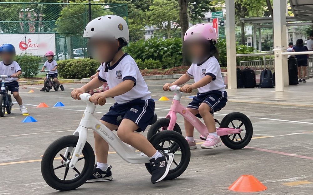 Pre-schoolers riding balance bikes through a cone course at a Momentum Academy session in Singapore