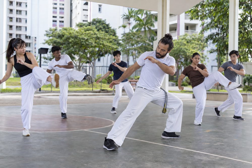Students practising Capoeira techniques with a Momentum Academy coach in Singapore