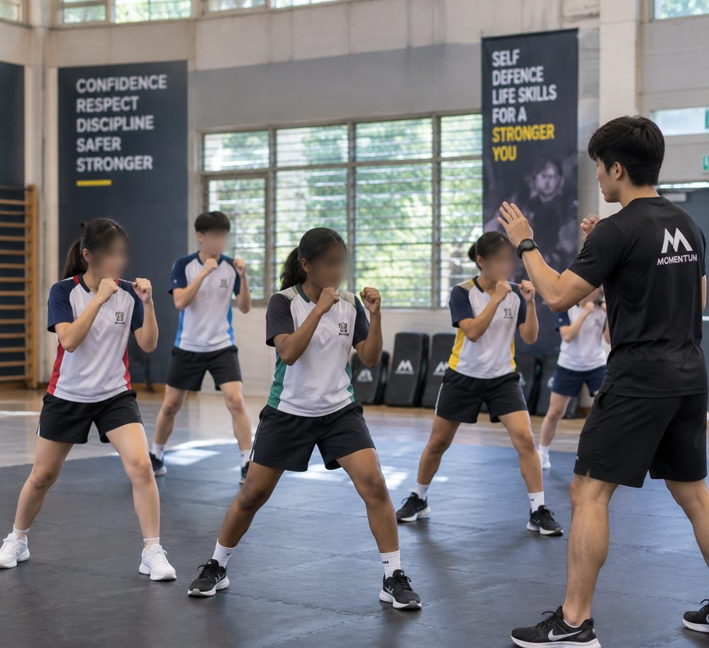Two students practising self-defence technique and control with a Momentum Academy coach in Singapore