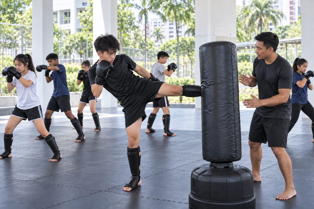 Students practising Mixed Martial Arts (MMA) techniques with a Momentum Academy coach in Singapore