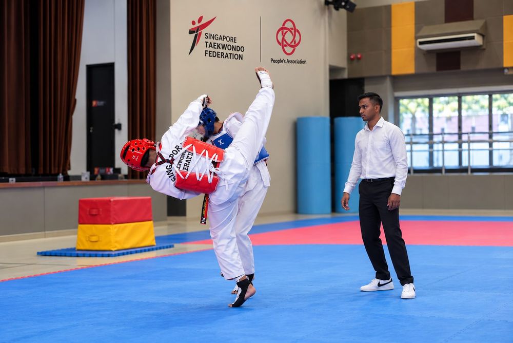 Students practising Taekwondo techniques with a Momentum Academy coach in Singapore
